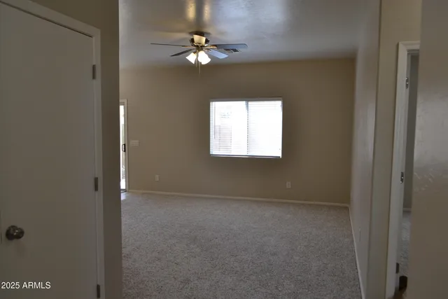 an empty room with windows and fan