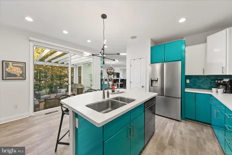 a kitchen with sink a refrigerator and chairs