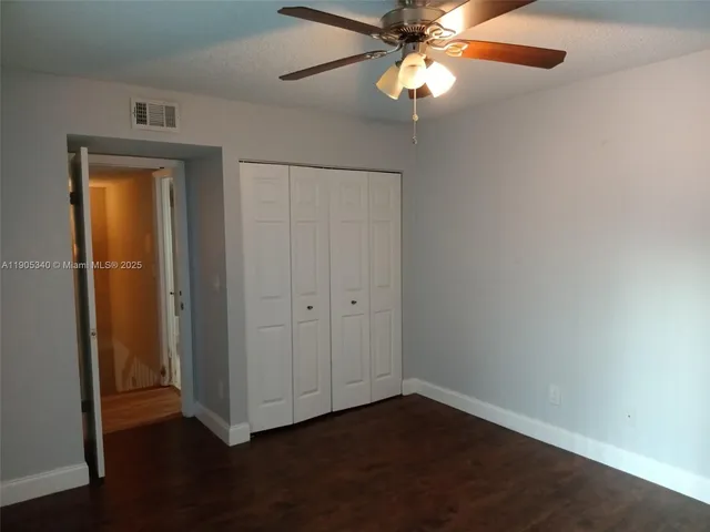 an empty room with wooden floor closet and windows