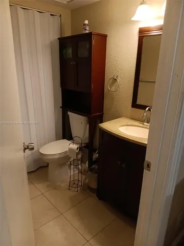 a bathroom with a sink a toilet a mirror and shower curtain