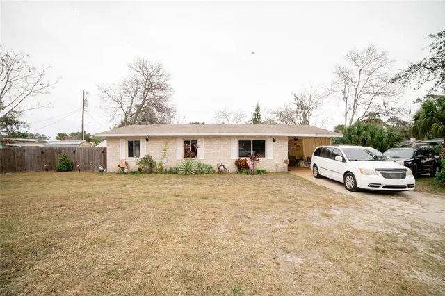 a view of a white house and a yard with a car parked