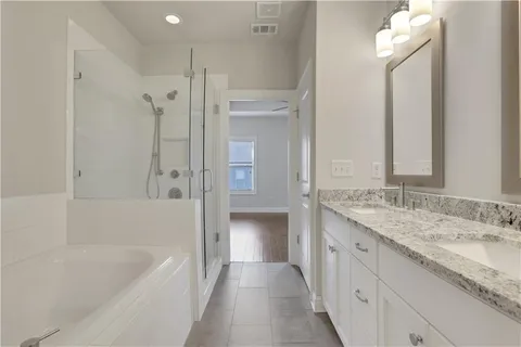 a bathroom with a granite countertop sink a bathtub and a mirror