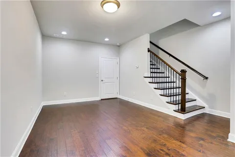 a view of an empty room with wooden floor and stairs