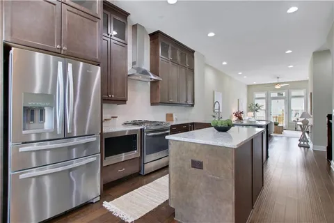 a kitchen with stainless steel appliances granite countertop a refrigerator a stove and a sink with wooden floor