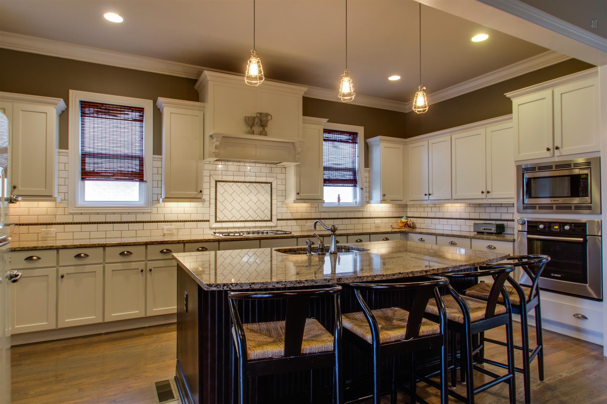1409 Eliot Road Franklin, TN 37064 - Photo 5 of 27 a kitchen with stainless steel appliances granite countertop a stove a sink a microwave a dining table and chairs with wooden floor