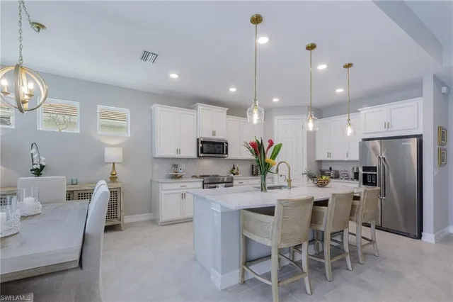 a kitchen that has a lot of white cabinets and stainless steel appliances