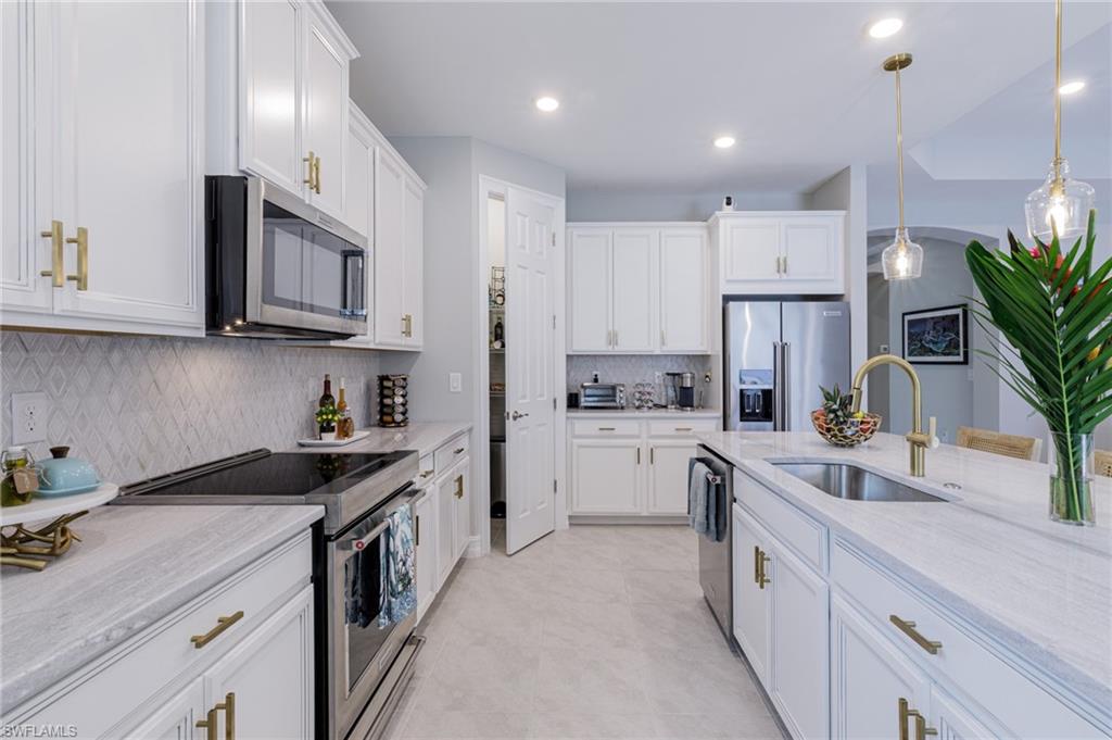 14614 Stillwater Way Naples, FL 34114 - Photo 17 of 47 a kitchen that has a lot of white cabinets and stainless steel appliances