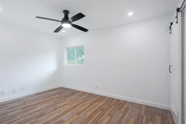 an empty room with wooden floor ceiling fan and window