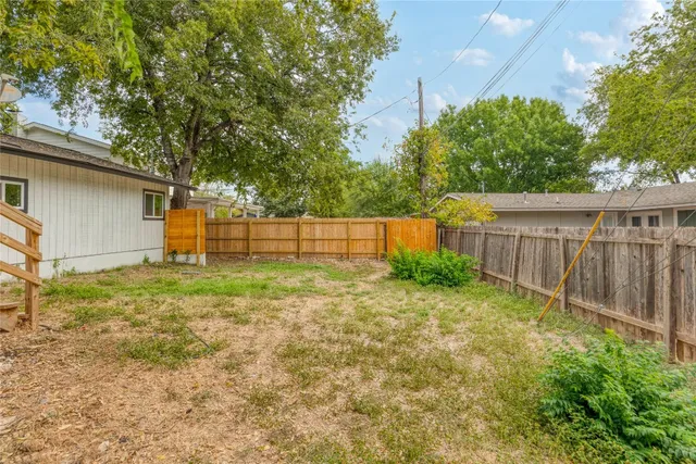 a view of backyard with wooden fence and trees