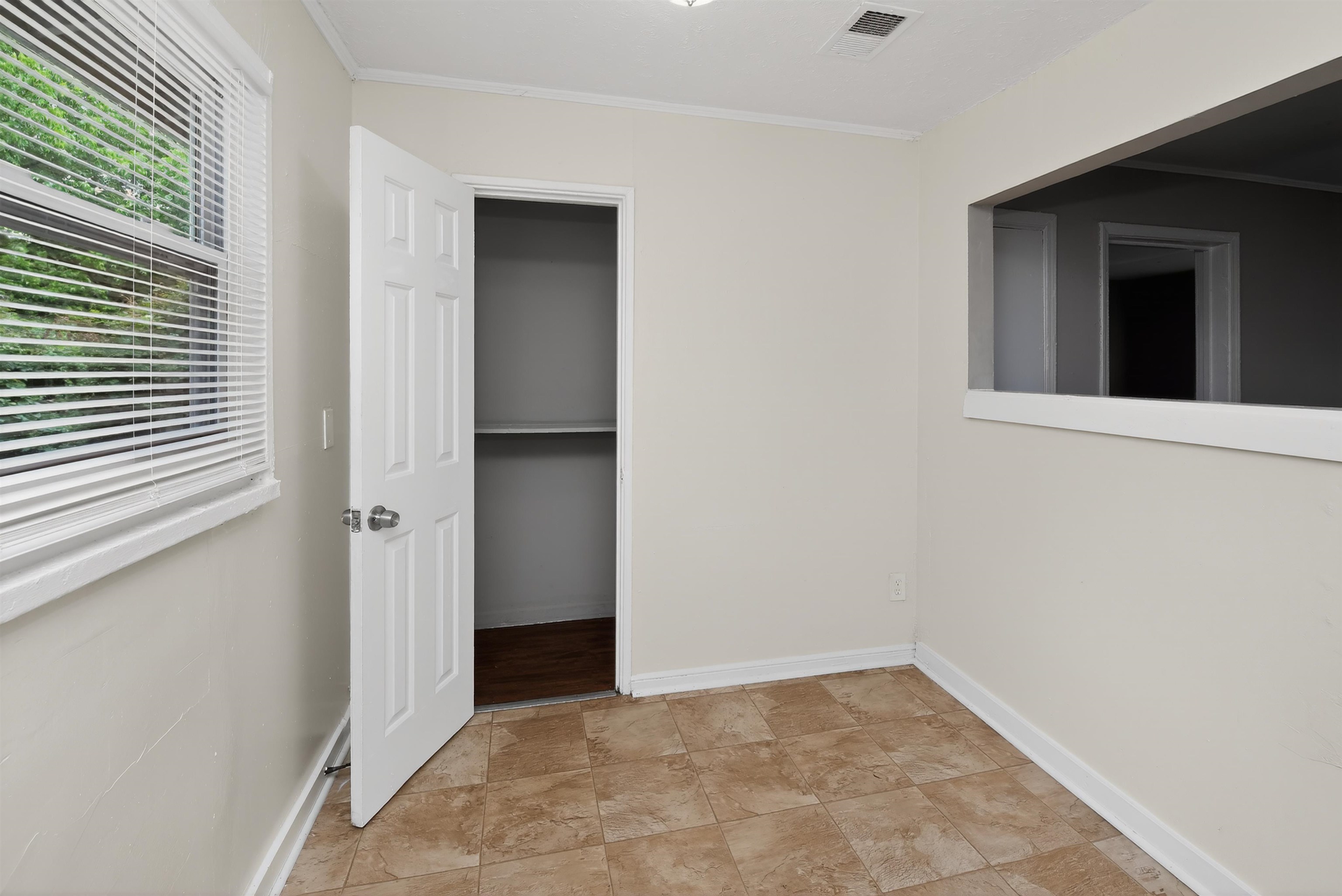 4838 Manson Road Memphis, TN 38109 - Photo 21 of 28 Room featuring tiled flooring, a window with blinds, a closet with an open six-panel door, and a wall cutout