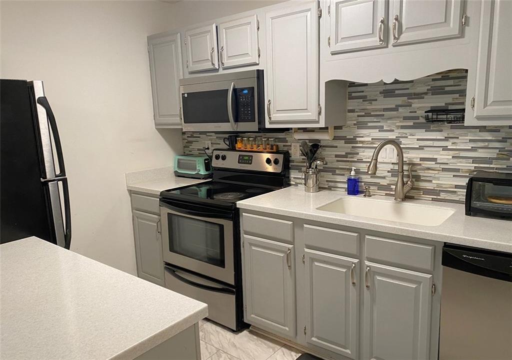 3934 Woodridge Way Tucker, GA 30084 - Photo 7 of 75 a kitchen with stainless steel appliances a sink a stove a microwave a refrigerator and cabinets