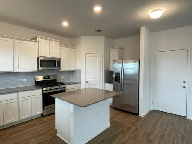 a kitchen with granite countertop a refrigerator and a stove top oven