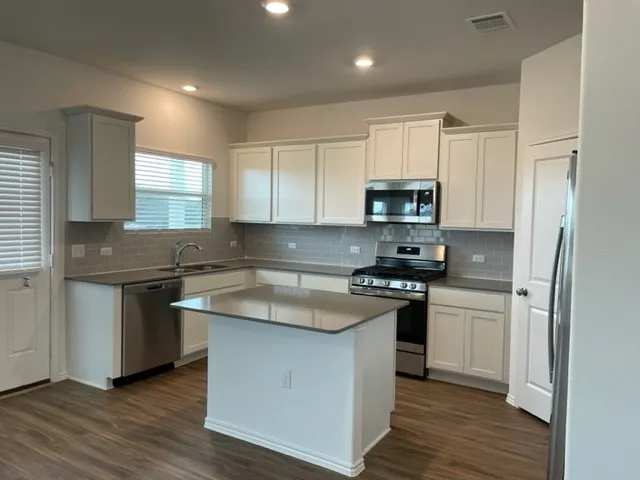 a kitchen with granite countertop white cabinets and stainless steel appliances
