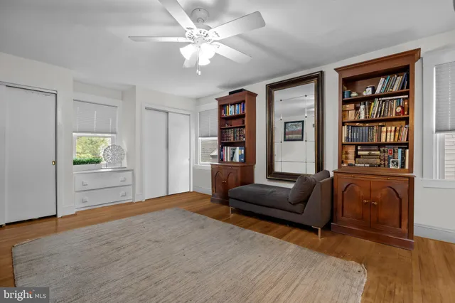 a living room with furniture and a bookshelf with wooden floor