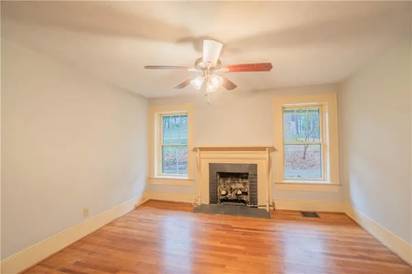 a view of a livingroom with a fireplace a ceiling fan and wooden floor