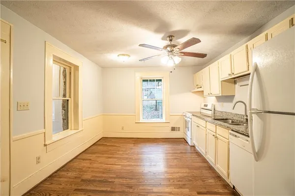 a kitchen with stainless steel appliances a stove top oven a refrigerator a sink and dishwasher with white cabinets
