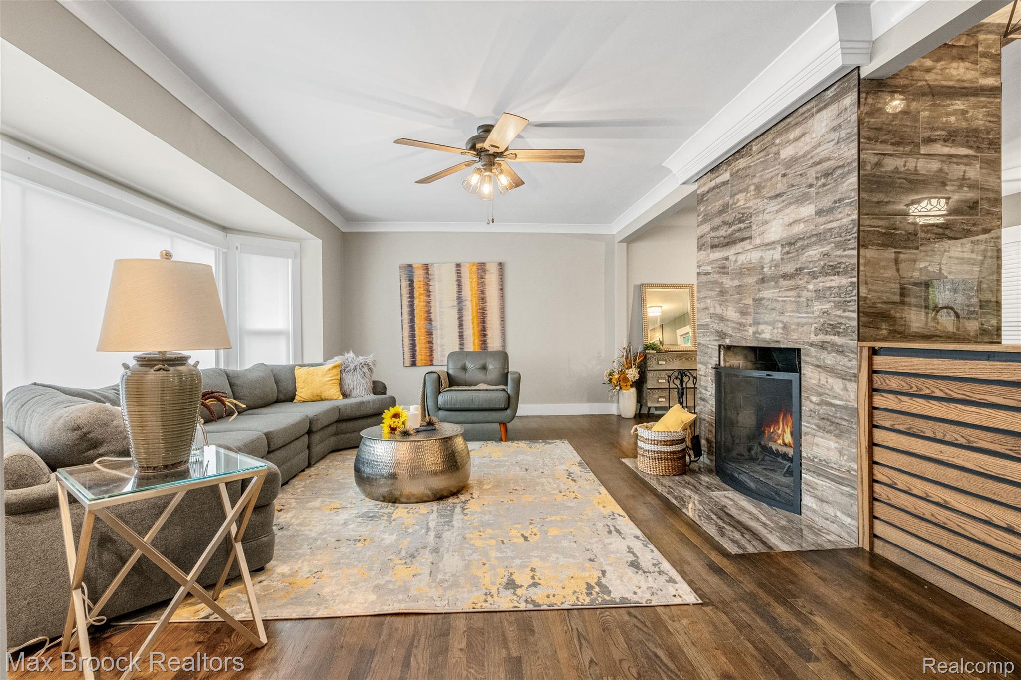 2905 Lahser Road Bloomfield Hills, MI 48304 - Photo 4 of 28 Living area featuring wood-finish flooring, a contemporary fireplace with a stone surround, crown molding, and a ceiling fan