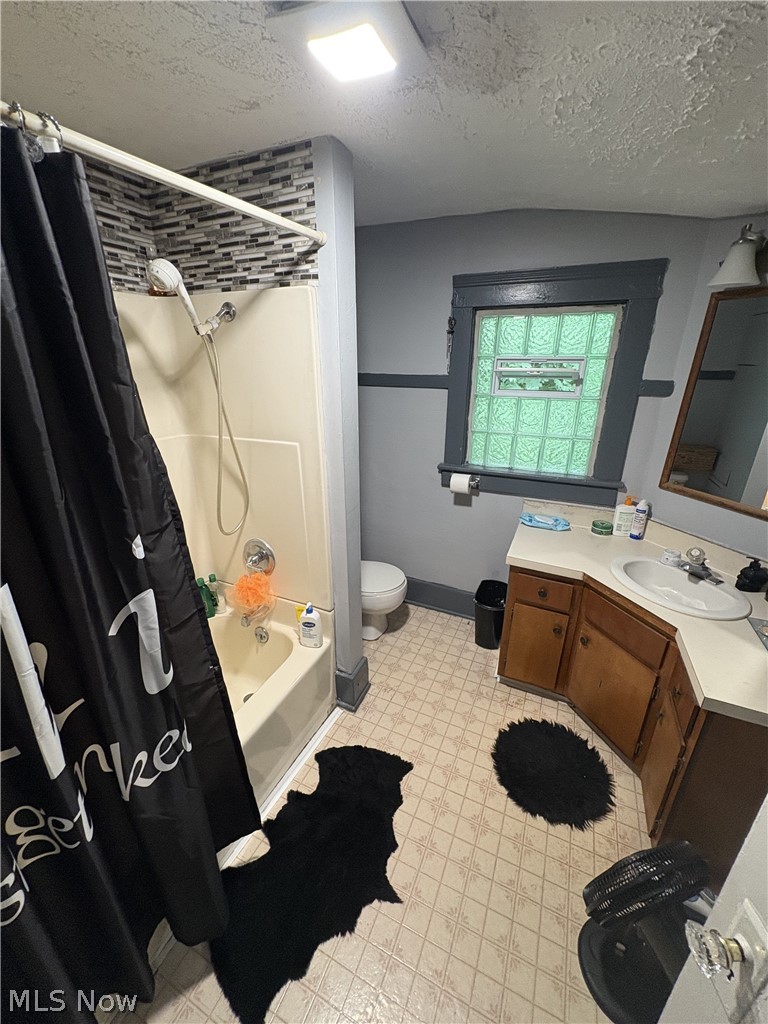 727 Wooster Road North Barberton, OH 44203 - Photo 27 of 37 729 (1-Bed) - Bathroom featuring a corner vanity with an integrated sink, a glass block window with an operable vent, and a wall-mounted light fixture above a framed mirror