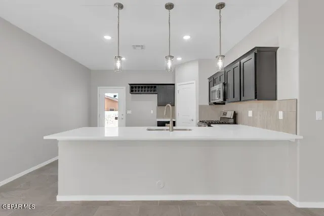 a large kitchen with a large counter top space appliances and cabinets