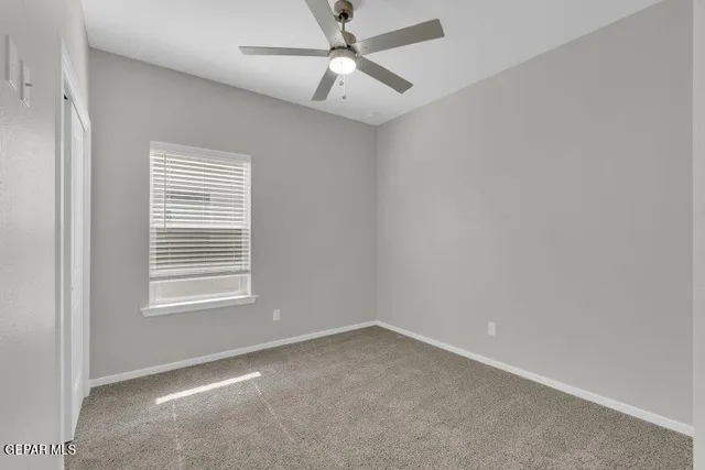 an empty room with a window and a fan