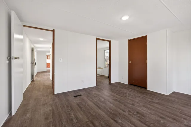 a view of an empty room with wooden floor and closet