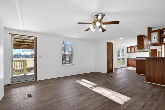 a view of a kitchen with wooden floor a sink a refrigerator and window