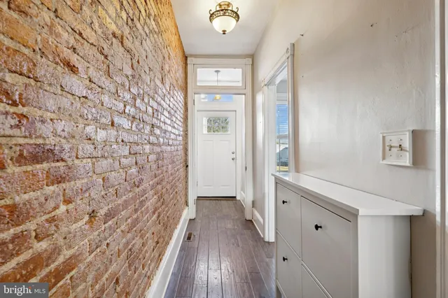 a view of a hallway with wooden floor and a bathroom