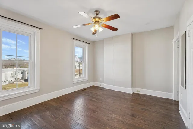 an empty room with wooden floor fan and windows