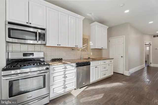 a kitchen with granite countertop cabinets stainless steel appliances and wooden floor