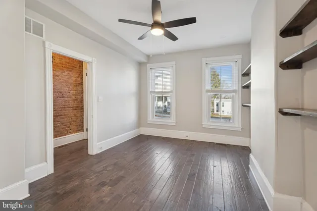 a view of an empty room with a window and wooden floor