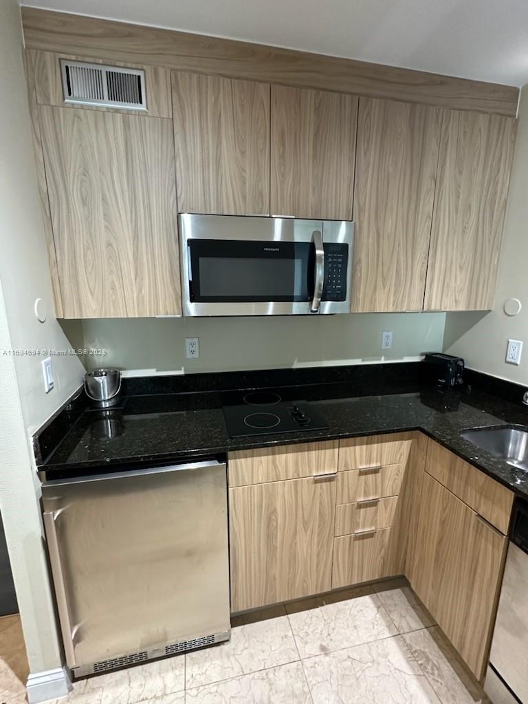 2670 East Sunrise Boulevard, Unit 905 Fort Lauderdale, FL 33304 - Photo 27 of 58 a kitchen with granite countertop white cabinets and stainless steel appliances