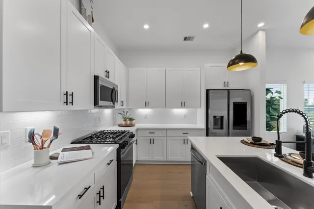 a kitchen with a sink a stove and chairs with wooden floor
