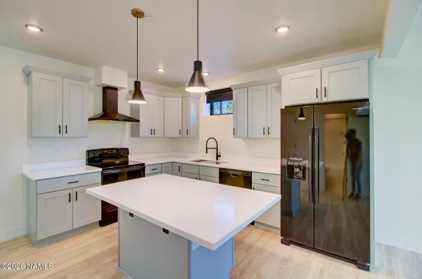 a kitchen with stainless steel appliances granite countertop a refrigerator a sink a stove and a cabinets