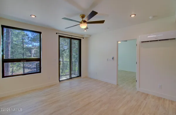an empty room with wooden floor fan and windows