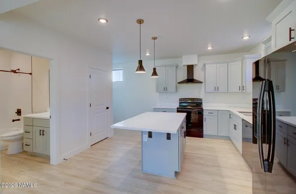 a kitchen with a refrigerator a sink dishwasher a stove and white cabinets with wooden floor