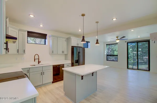a open kitchen with stainless steel appliances granite countertop a sink dishwasher a refrigerator and a dining table with wooden floor