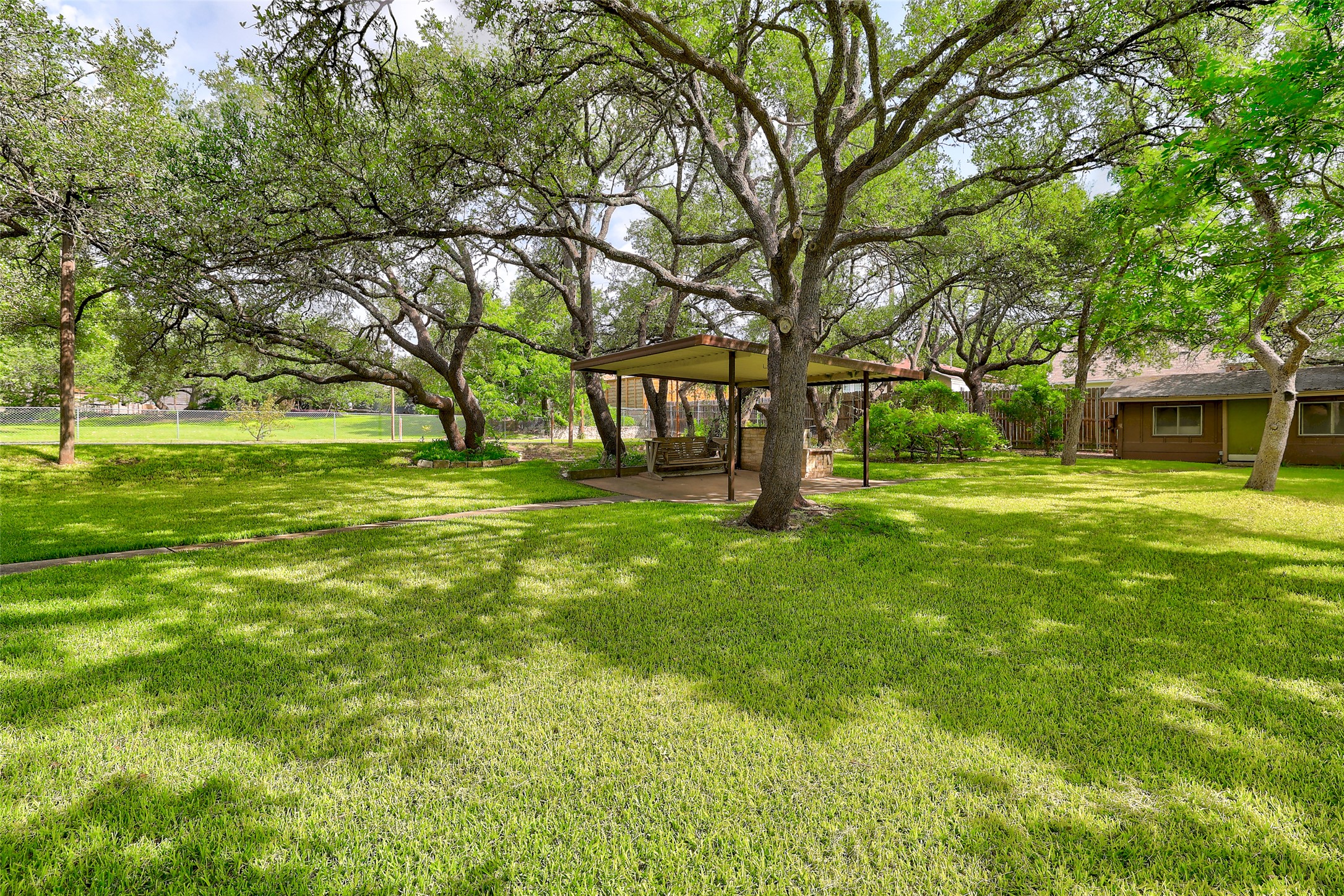 8606 Thunderbird Road, Unit A & B Austin, TX 78736 - Photo 31 of 34 Lush green lawn and mature trees provide ample shade, perfect for outdoor enjoyment.