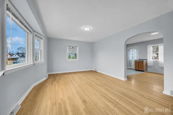 a view of an empty room with window and wooden floor