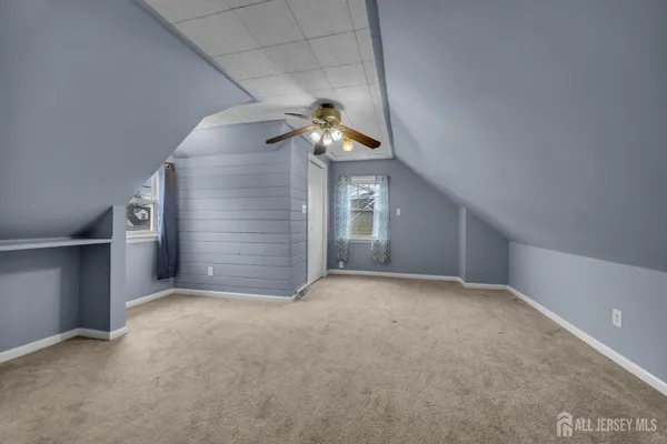 an empty room with a chandelier fan and windows