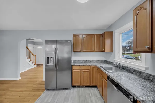 a kitchen with stainless steel appliances granite countertop a sink a stove cabinets and wooden floor