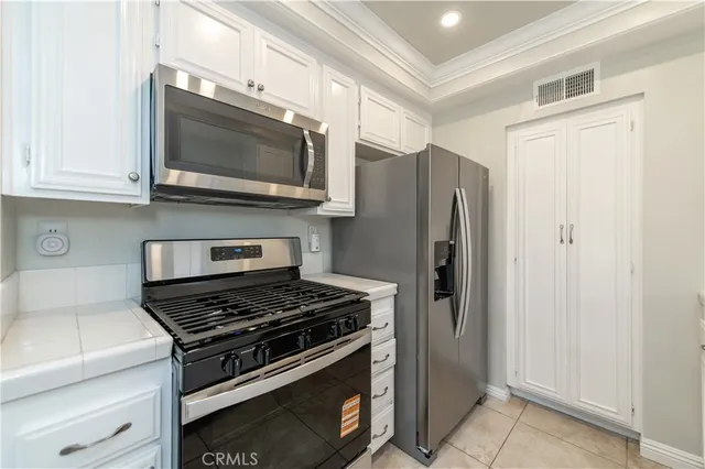 a kitchen with stainless steel appliances white cabinets and a stove top oven