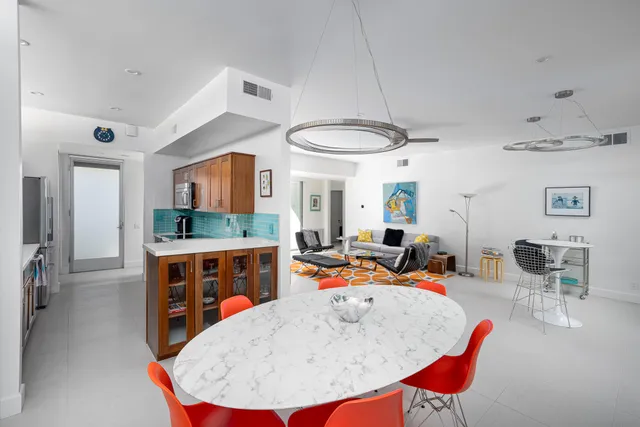 a large white kitchen with a stove a sink a dining table and chairs