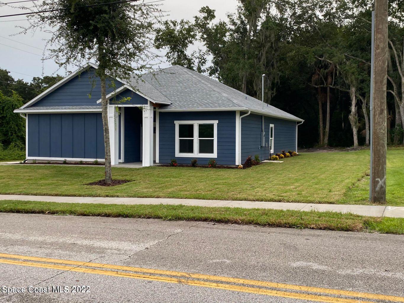2498 Mitchell Avenue Mims, FL 32754 - Photo 2 of 18 a front view of a house with a garden and trees