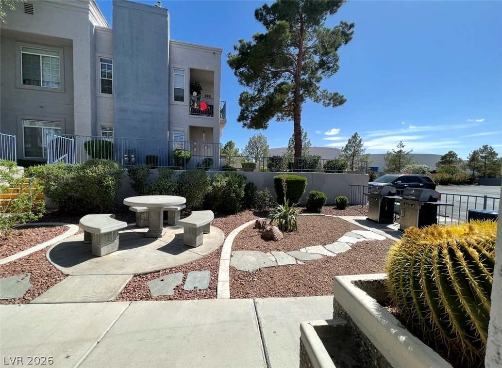 2201 Ramsgate Drive, Unit 915 Henderson, NV 89074 - Photo 12 of 36 A welcoming outdoor patio area with a stone table, benches, and landscaping.
