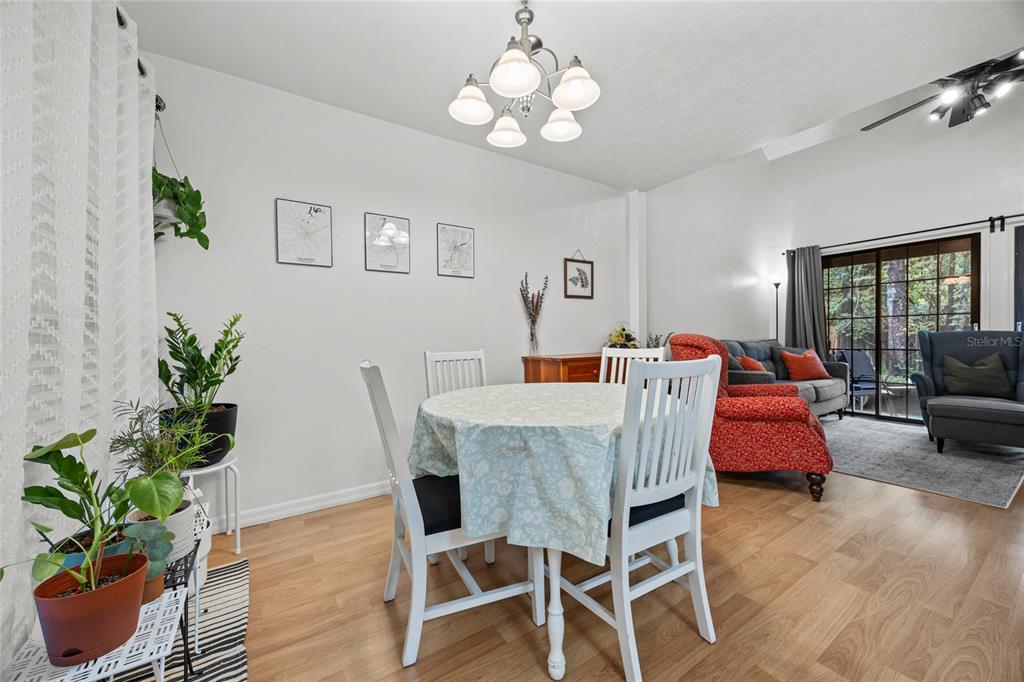 5733 Southwest 10th Place Gainesville, FL 32607 - Photo 7 of 23 a dining room with wooden floor a chandelier a glass table and chairs