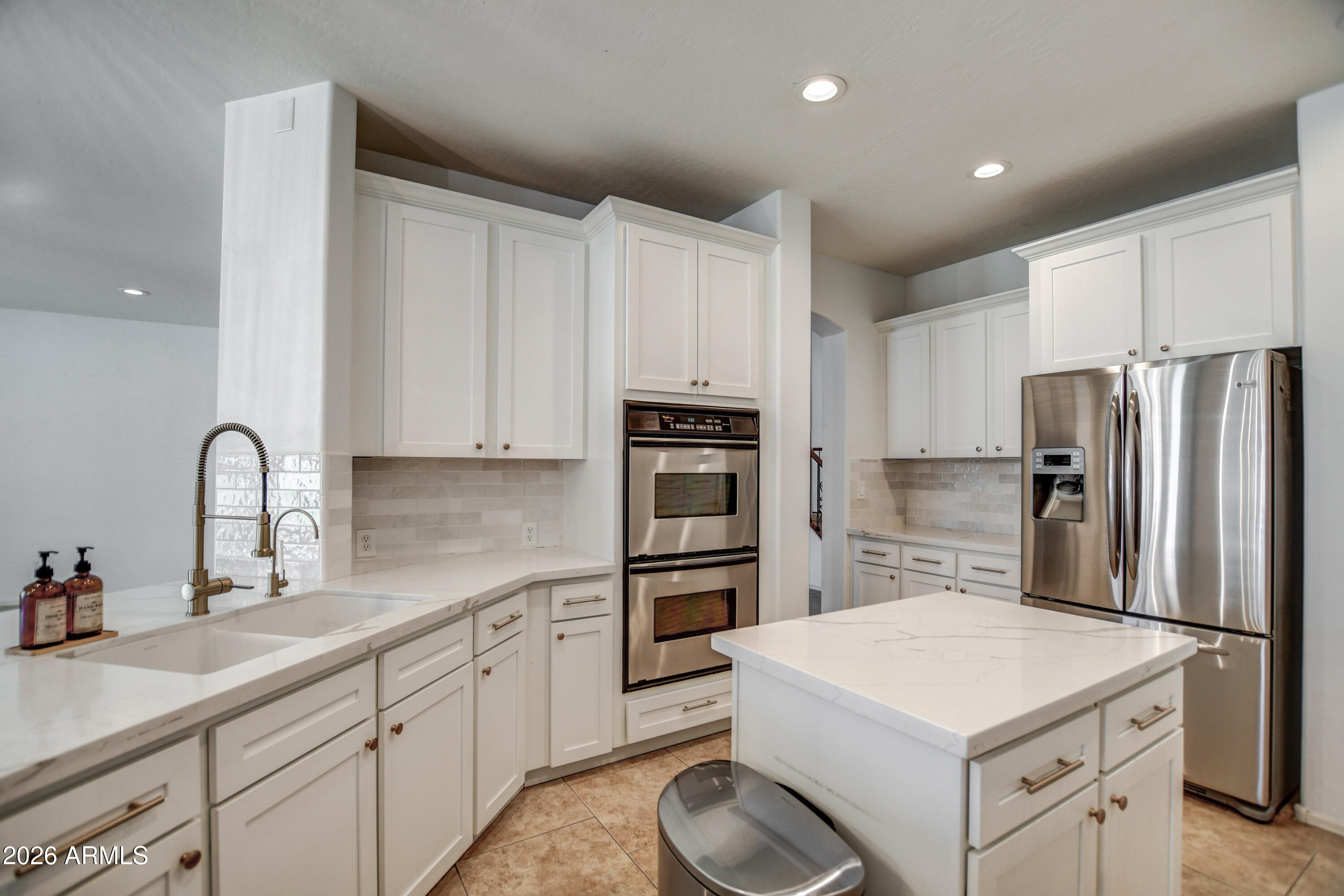 3078 East Muirfield Street Gilbert, AZ 85298 - Photo 36 of 92 a kitchen that has a refrigerator a sink and white cabinets