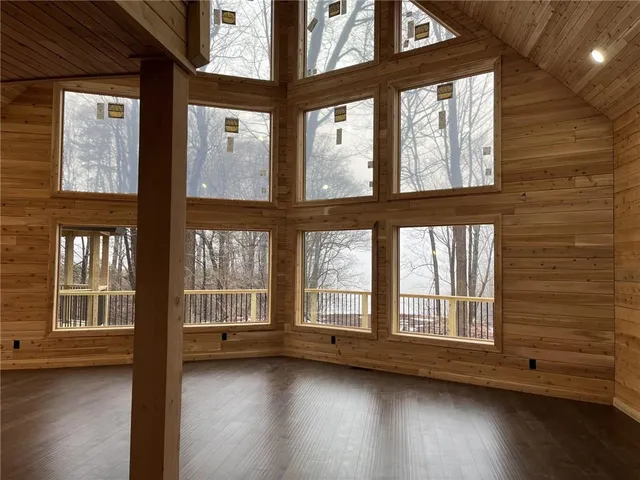 a view of an empty room with wooden floor and windows