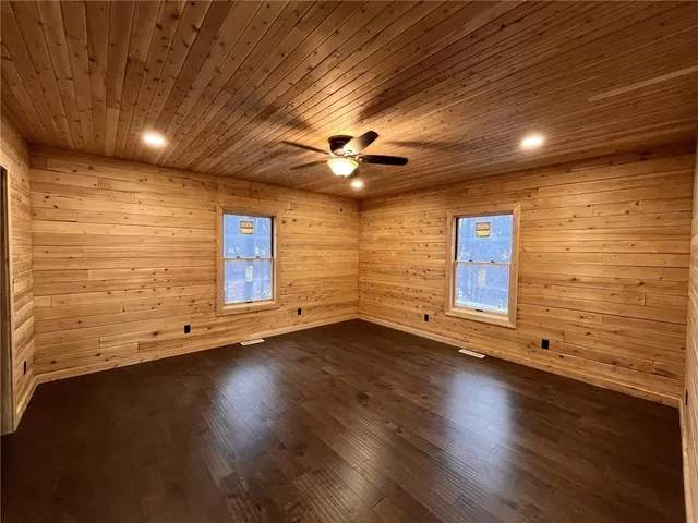 a view of an empty room with wooden floor and a ceiling fan
