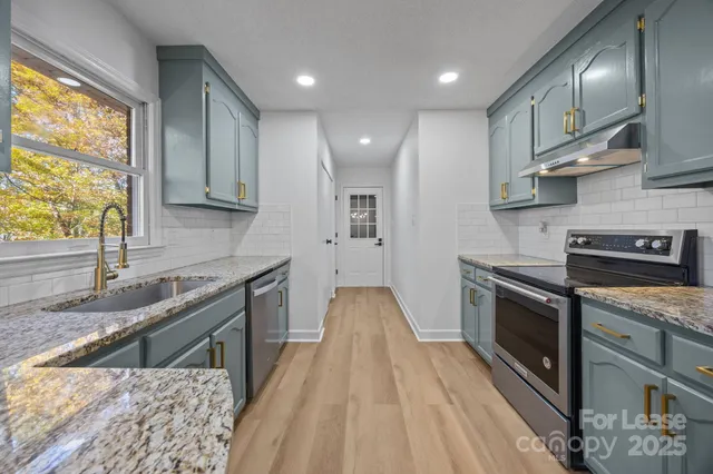 a kitchen with stainless steel appliances granite countertop a stove a sink and a microwave