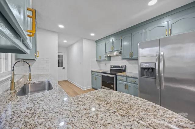 a kitchen with granite countertop a refrigerator and a sink